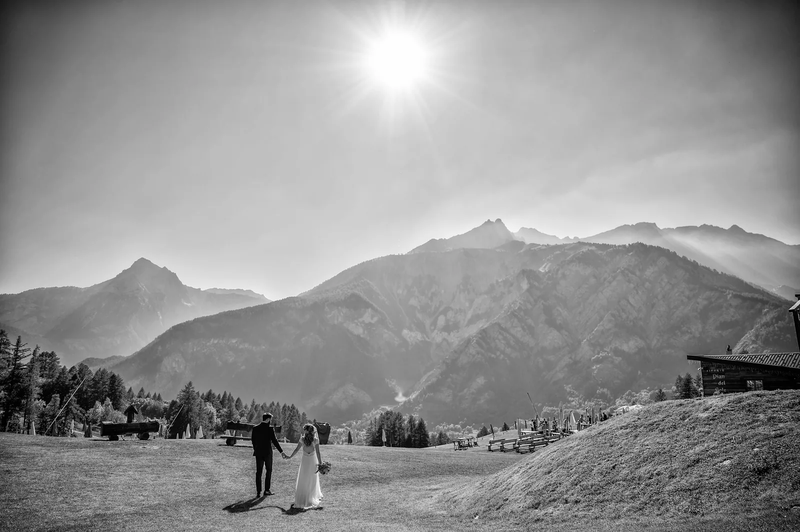 A couple walking across an alpine meadow under the sun, Bardonecchia, black and white