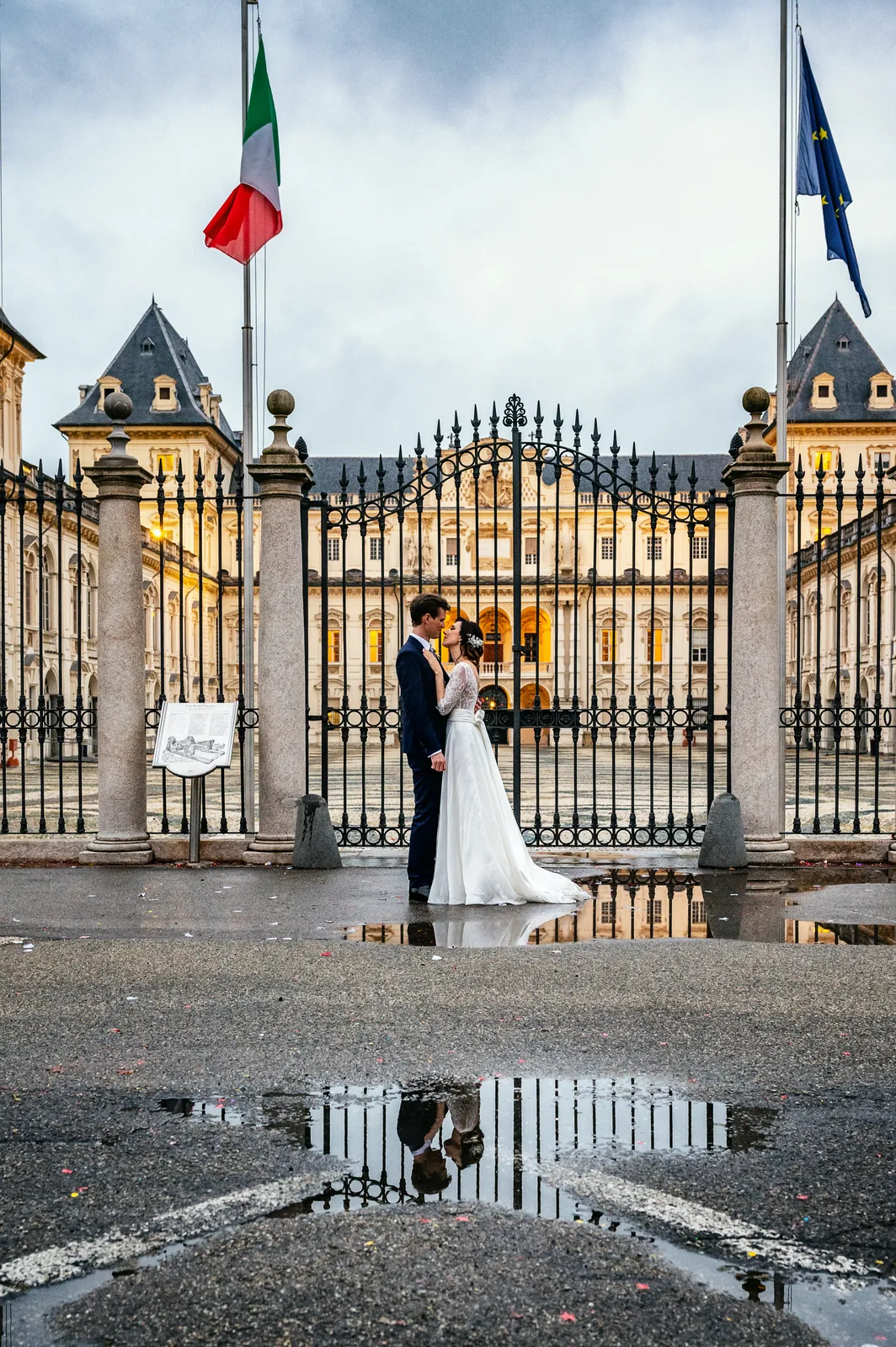 The couple at the gates of Castello del Valentino under the Italian flag, reflected in the rain, Turin