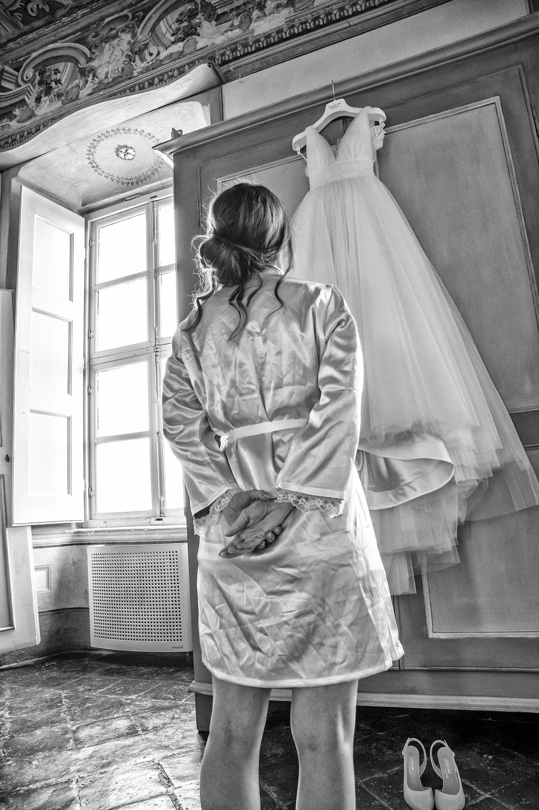A bride looking at her wedding dress by the window, Castello della Costa, black and white