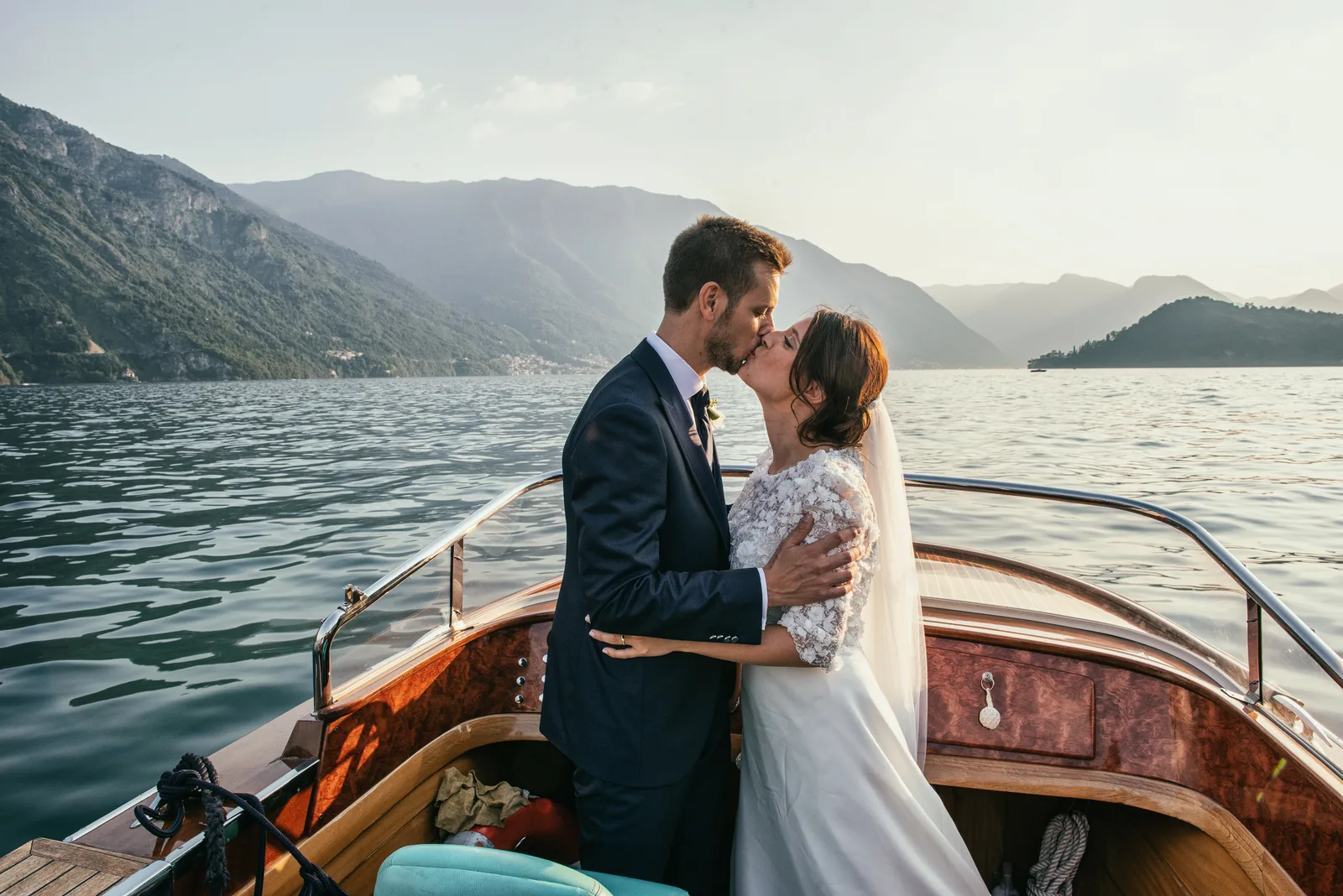 The couple kissing on a wooden motorboat on Lake Como
