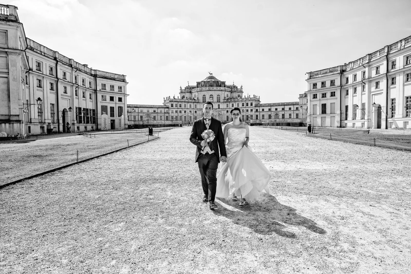 The couple walking along the axis of the Palazzina di Stupinigi, black and white