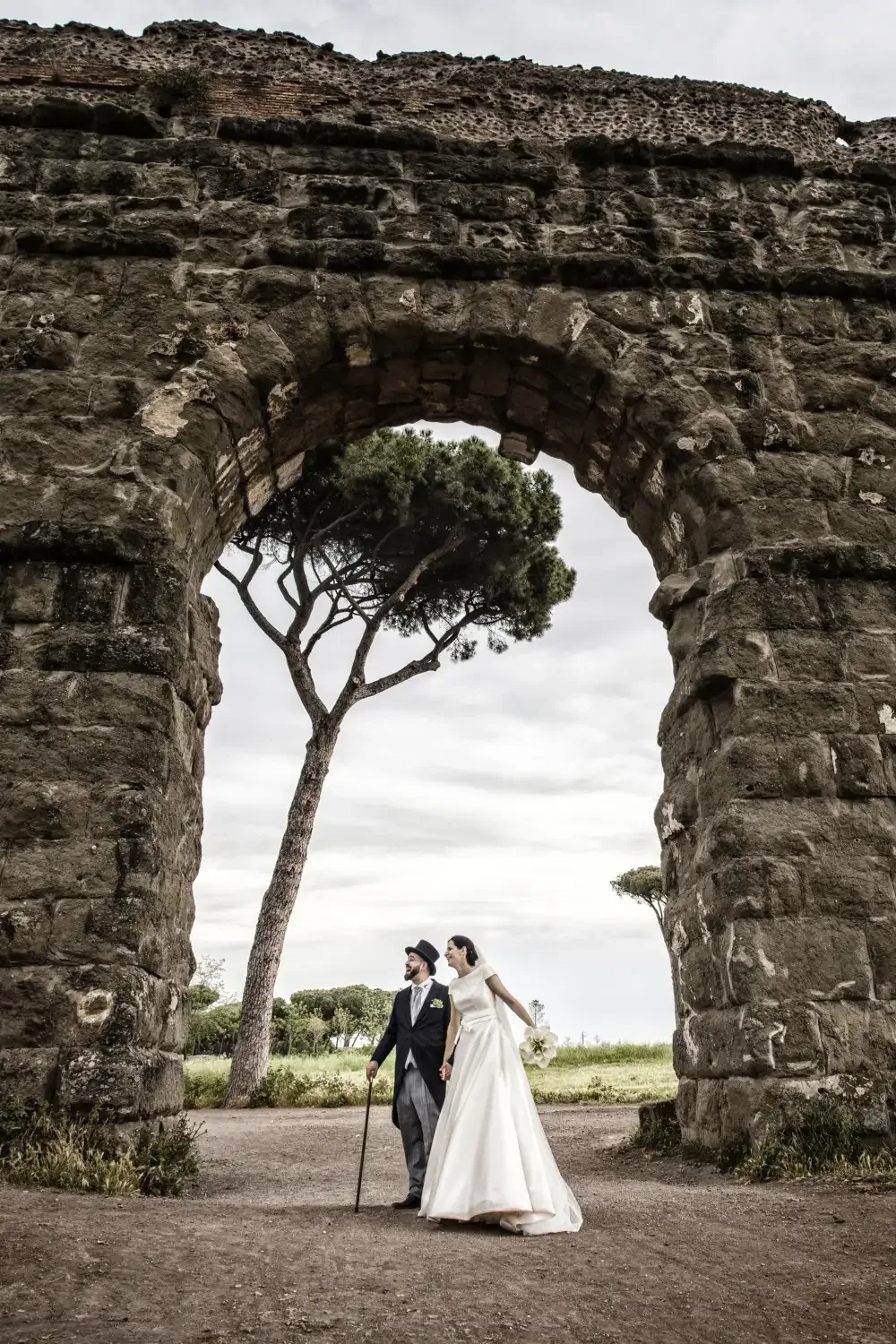 The couple beneath an arch of an ancient Roman aqueduct