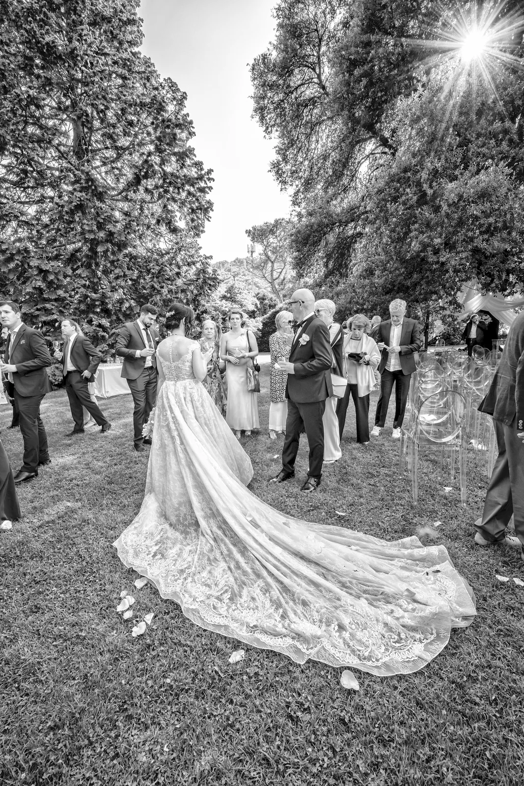 A long bridal train on the lawn among guests, Villa Frua, black and white