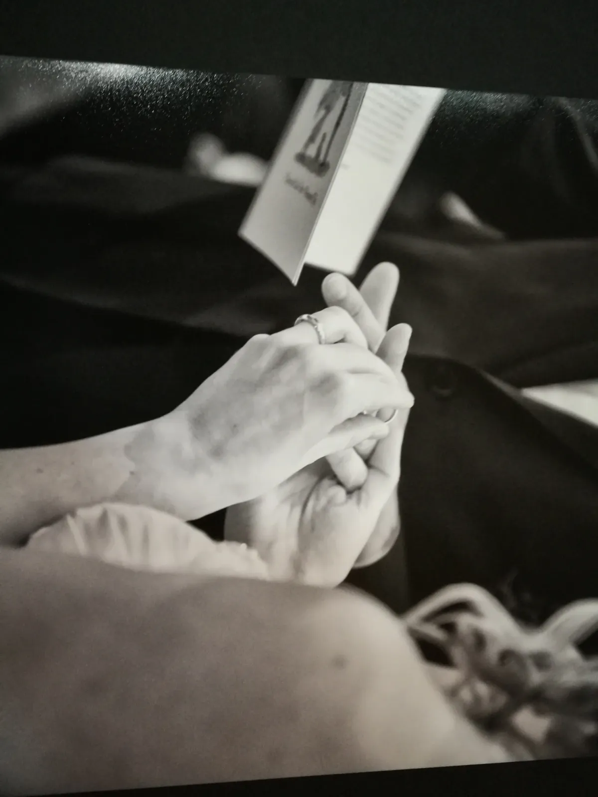 Pagina di un album di matrimonio con le mani degli sposi e le fedi, bianco e nero