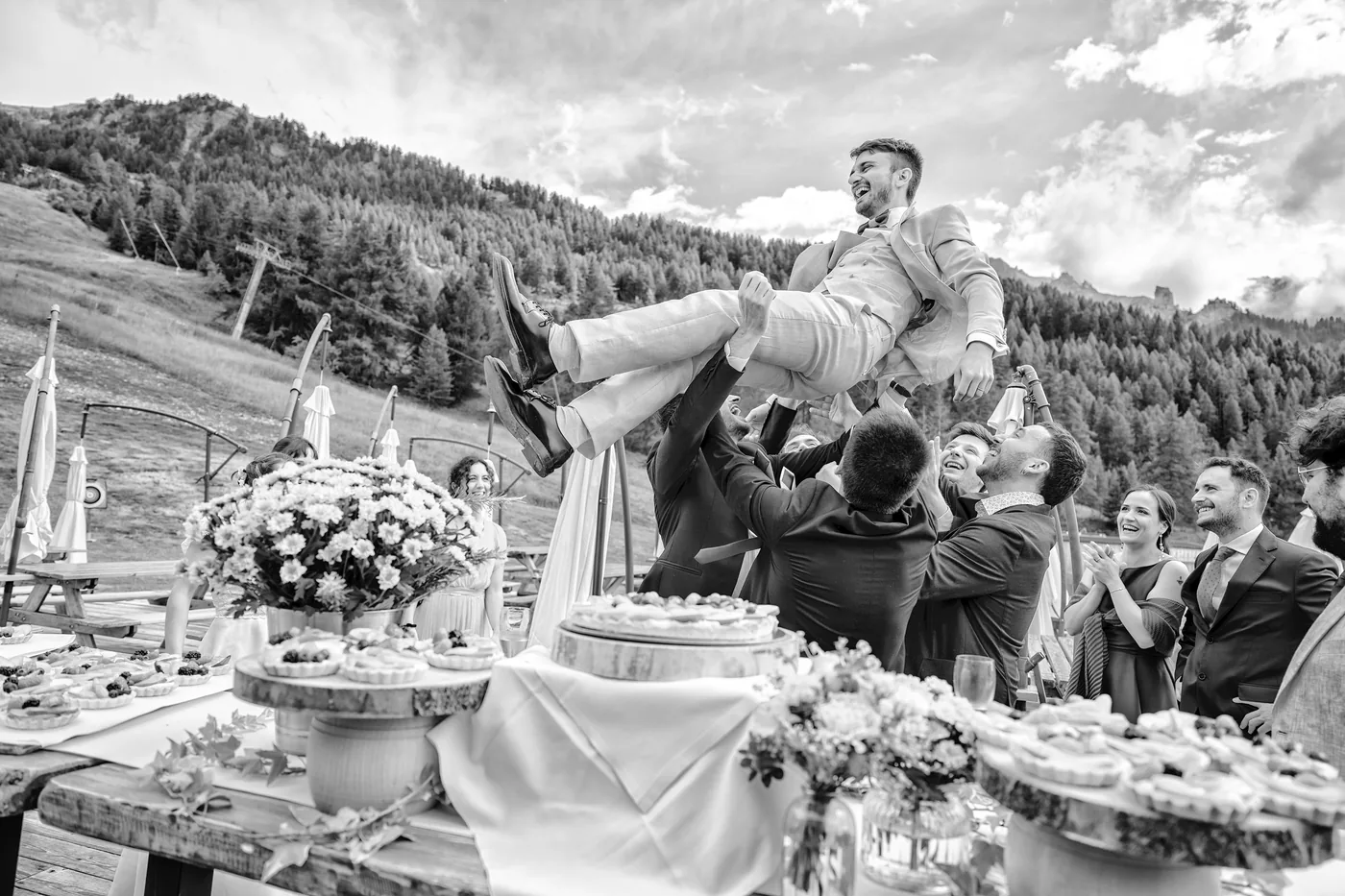 Sposo sollevato dagli amici al taglio della torta in bianco e nero, matrimonio Chesal Bardonecchia