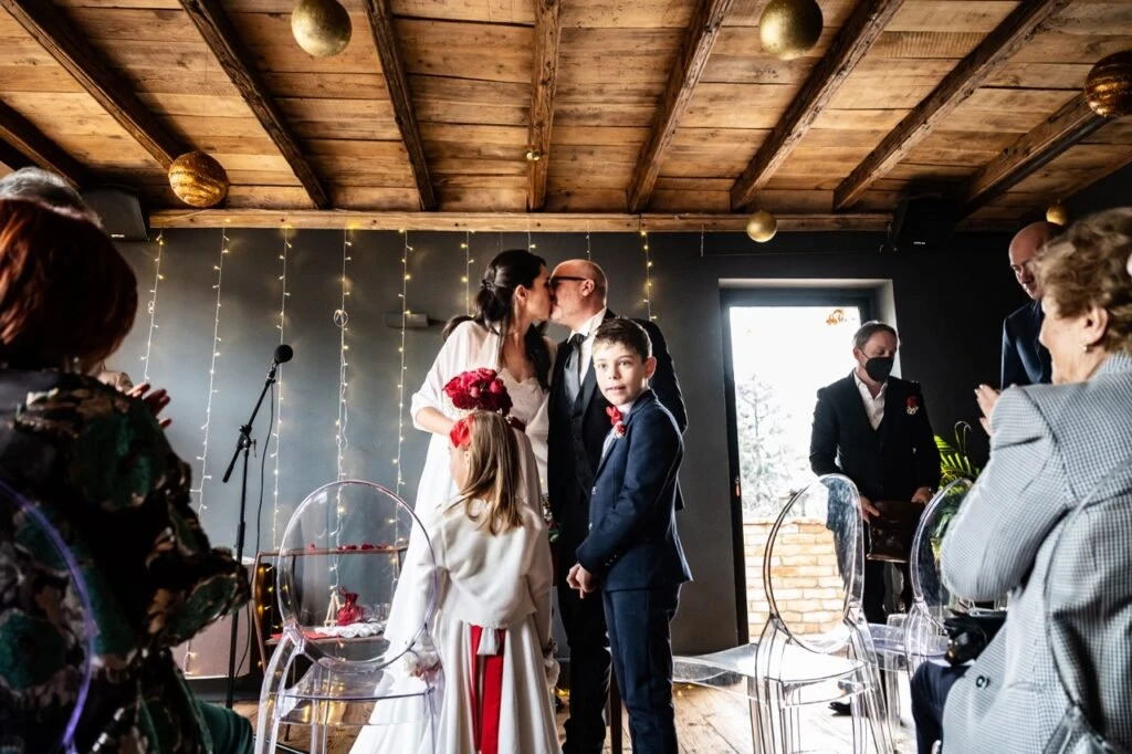 Bacio degli sposi con i bambini intorno, momento di partecipazione collettiva durante il matrimonio