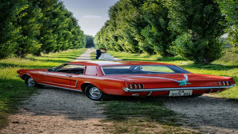 Sposi davanti ad auto vintage rossa a Stupinigi