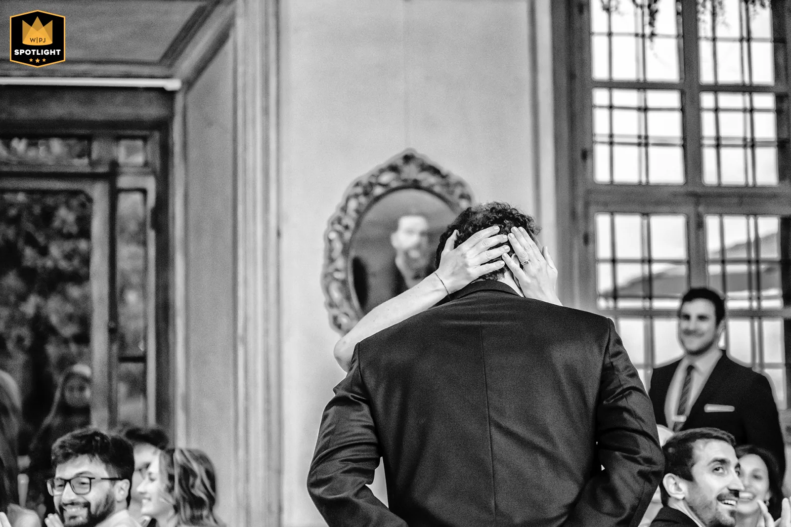Elisabetta Rosso fotografa, WPJA Spotlight 2026: sposo abbracciato di spalle, mani della sposa e riflesso nello specchio, Palazzo La Marmora, Biella (bianco e nero)