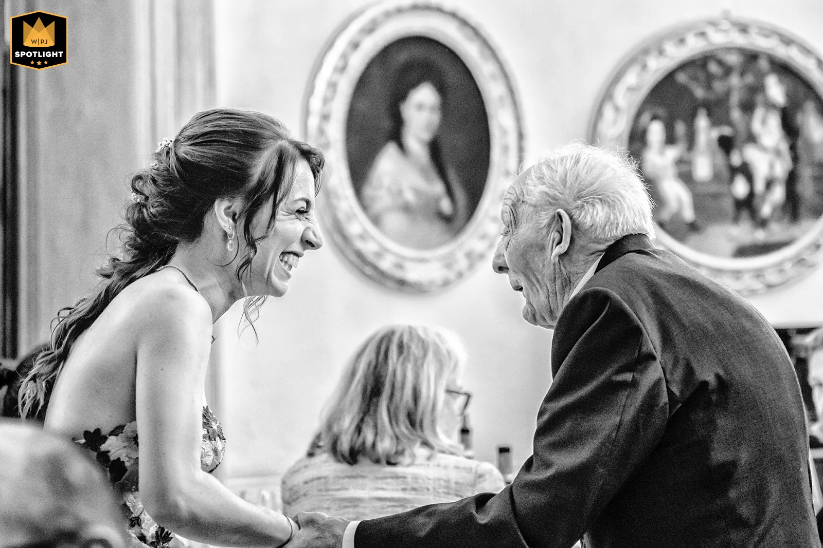 Elisabetta Rosso fotografa, WPJA Spotlight 2026: sposa che ride stringendo le mani di un invitato anziano, Palazzo La Marmora, Biella (bianco e nero)