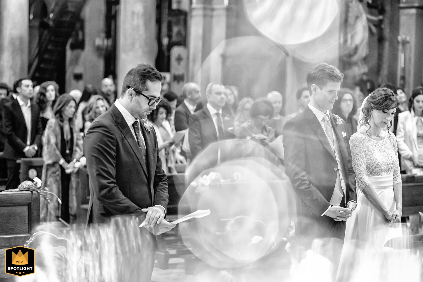 Elisabetta Rosso fotografa, WPJA Spotlight 2026: lettura in chiesa con gli sposi a mani giunte e riflessi di luce, Torino (bianco e nero)